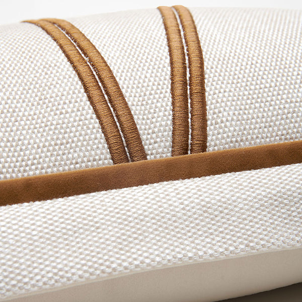 Close-up of a woven cushion or pillow in off-white fabric with two vertical tan stitched bands and a matching tan horizontal trim.7