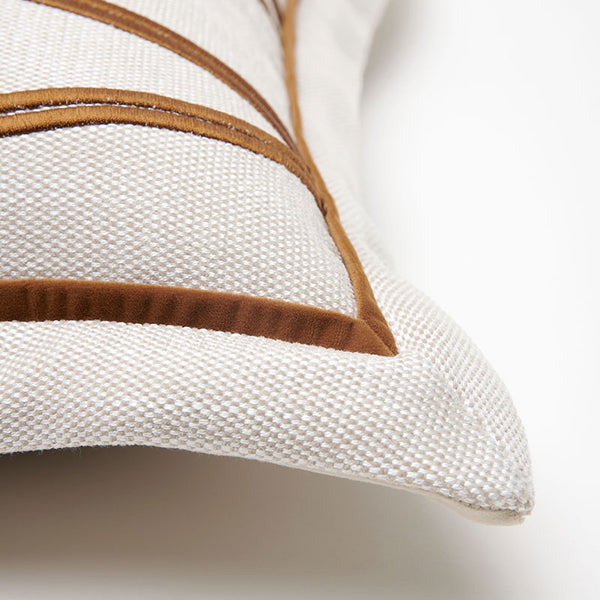 Close-up of a woven throw pillow in off-white fabric with brown embroidered geometric lines, shown on a clean white background.6